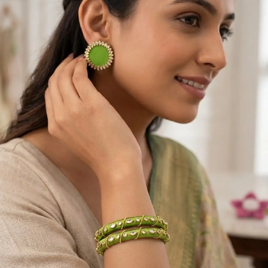 Close-up of a model wearing a handcrafted parrot green silk thread jewelry set, featuring exactly two kundan-embellished bangles and matching circular stud earrings, styled with a beige and gold ethnic outfit.